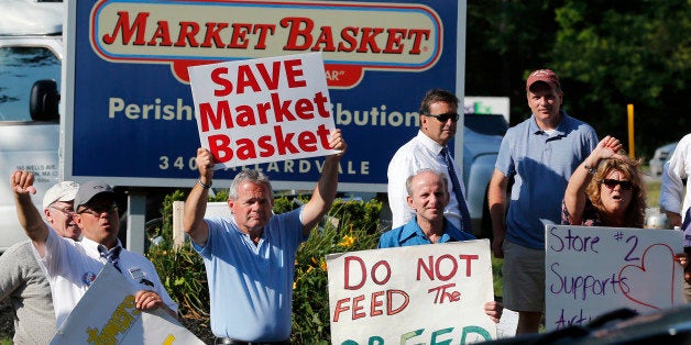 Protesters hold signs and taunt a car entering the site of a Market Basket Supermarket job fair in Andover, Mass., Wednesday, Aug. 6, 2014. Market Basket employees and their supporters are calling for the reinstatement of their fired CEO, even as the company is in the midst of a three-day job fair to replace employees who have refused to work during a revolt that is costing the supermarket chain millions. (AP Photo/Elise Amendola)