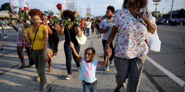 FILE - In this Aug. 18, 2014 file photo, a little girl holds a rose as she marches with protesters in Ferguson, Mo. The Aug. 9 shooting of Michael Brown by police touched off rancorous protests in the St. Louis suburb where police have used riot gear and tear gas to disperse crowds turning daily life on its head. (AP Photo/Jeff Roberson, File)