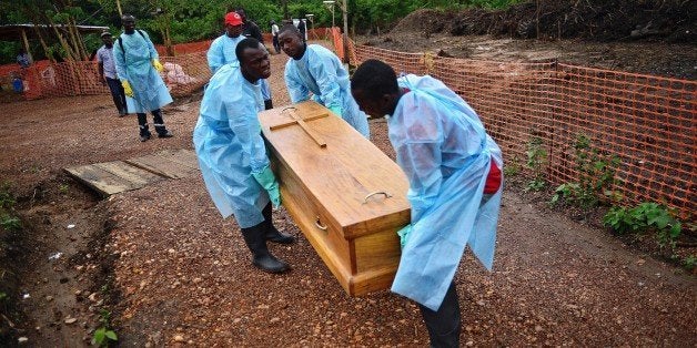 Sierra Leonese government burial team members wearing protective clothing carry the coffin of an Ebola victim on August 14, 2014 at Medecins Sans Frontiere facility in Kailahun. The victim is Dr Modupeh Cole, Sierra Leone's second senior physician to die of Ebola. Kailahun along with the Kenema district is at the epicentre of the worst epidemic of Ebola since its discovery four decades ago. The death toll stands at more than 1,000. The Ebola epidemic in West Africa claimed a fourth victim in Nigeria on August 14 while the United States ordered the evacuation of diplomats' families from Sierra Leone and analysts warned of a heavy economic toll on the stricken region. AFP PHOTO/Carl de Souza (Photo credit should read CARL DE SOUZA/AFP/Getty Images)