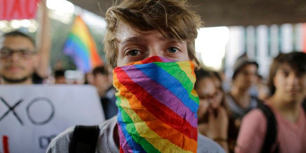 A man cover his face with a scarf with the colors of the gay movement during a protest against the homophobic comments of presidential candidate Levy Fidelix, in Sao Paulo, Brazil, Tuesday, Sept. 30, 2014. Fidelix a minor character in Brazil's election race faced a firestorm of criticism on Monday after saying during a presidential debate that the country needs to stand up against gay people who should receive psychological help far away from the general population. The comments drew no reaction from the leading candidates during the nationally televised debate late Sunday. But online and on social media tens of thousands of people denounced Fidelix as homophobic and hateful. (AP Photo/Nelson Antoine)