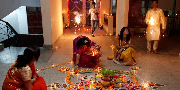 Indian Hindu woman lights earthen lamps to celebrate Diwali, the Hindu festival of lights, in Allahabad, India,Sunday, Nov. 3, 2013. Hindus across the country are celebrating Diwali where people decorate their homes with lights and let off fireworks. (AP Photo/ Rajesh Kumar Singh)