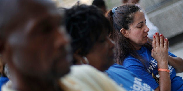 Mayra Valle prays at a prayer vigil for Michael Brown outside the McNamara Federal Building in Detroit Monday, Aug. 25, 2014. Brown, a black 18-year-old who was unarmed, he was shot Aug. 9 in Ferguson, Mo., by Officer Darren Wilson, who is white. A grand jury is considering evidence in the case and a federal investigation is also underway. (AP Photo/Paul Sancya)