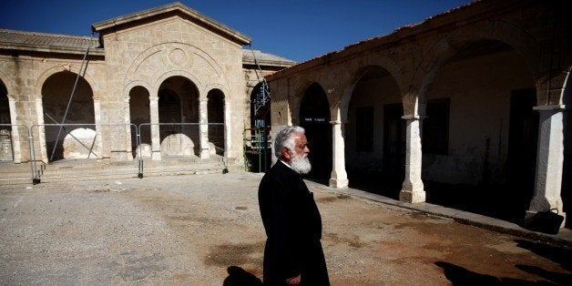 A Greek Cypriot Orthodox priest monitors restoration work being done at the Apostolos Andreas Monastery in North Cyprus at Ri