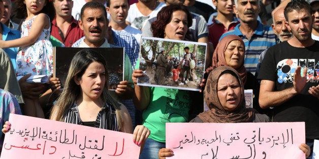 Kurdish citizens who live in Lebanon hold Arabic placards that read, "To be Yazidi means love, accord and peace" and "No to killing the Yazidi sect by Daesh" during a demonstration against the Islamic State group, in front of the UN building, in downtown Beirut, Lebanon, Monday Sept. 15, 2014. An activist group and a Kurdish official say heavy clashes are taking place in northeastern Syria, with Kurdish fighters capturing about a dozen villages from Islamic militants. Kurdish fighters and members of the Islamic State group have been fighting each other for more than a year in northern Syria. (AP Photo/Hussein Malla)