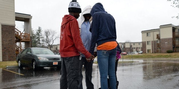 A man prays with his children at a makeshift memorial on November 23, 2014 in Ferguson, Missouri, where 18-year-old black tee