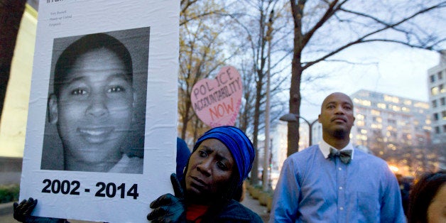 CORRECTS THE ID OF THE MALE ON POSTER TO TAMIR RICE - Tomiko Shine holds up a picture of Tamir Rice, the 12 year old boy fatally shot on Nov. 22 by a rookie police officer, during a protest in response to a grand jury's decision in Ferguson, Mo. to not indict police officer Darren Wilson in the shooting death of Michael Brown, an unarmed black man, at the Department of Justice in Washington, Monday, Dec. 1, 2014. Protesters across the U.S. have walked off their jobs or away from classes in support of the Ferguson protesters. Rice's death has also sparked community demonstrations against police shootings. (AP Photo/Jose Luis Magana)