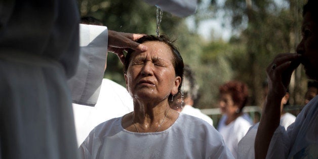 A Christian worshipper from Peru is baptized by a priest in the Jordan River, in Yardenit, northern Israel near the Sea of Galilee, Thursday, June 19, 2014 where it is believed Jesus Christ was baptized by John the Baptist. (AP Photo/Ariel Schalit)