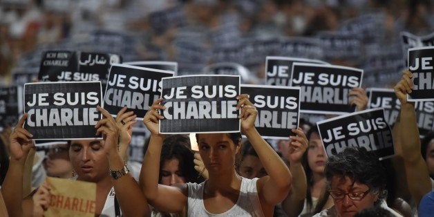 Members of Sydney's French community gather in the heart of the city to hold aloft banners reading 'Je Suis Charlie' (I am Charlie) on January 8, 2015, in tribute to the victims killed after gunmen opened fire in the offices of French satirical weekly Charlie Hebdo in Paris the day before. The vigil, just metres from where two hostages and a gunman died after a cafe siege in Sydney's Martin Place less than a month ago, saw many French and Australians carrying white and black 'Je Suis Charlie' placards. AFP PHOTO/Peter PARKS (Photo credit should read PETER PARKS/AFP/Getty Images)