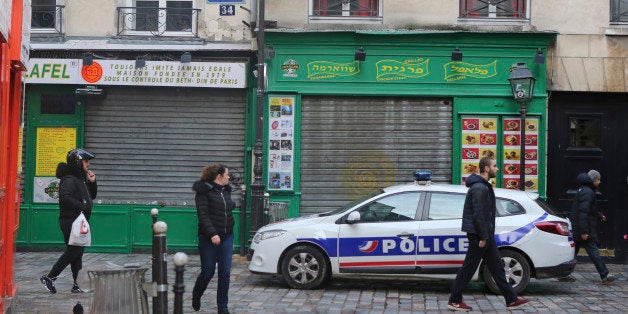 A police vehicle patrols in the Rue des Rosiers street, located in the heart of Paris Jewish quarter, in Paris, Friday, Jan. 9, 2015. Police ordered all shops closed in a famed Jewish neighborhood in central Paris far from the attacks, as Investigators are scrutinizing the recent past of two brothers with al-Qaida sympathies, as a manhunt for the suspects in the newsroom massacre at a satirical French weekly enters its third day. (AP Photo/Remy de la Mauviniere)