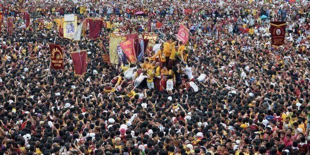 Thousands of devotees try to touch the religious icon of the Black Nazarene during the annual religious procession in Manila on January 9, 2015. Hundreds of thousands of Catholics joined the parade on January 9 of a centuries-old icon of Jesus Christ in a colourful display of religious fervour a week before Pope Francis visits the Philippines, Asia's Christian bastion. AFP PHOTO / TED ALJIBE (Photo credit should read TED ALJIBE/AFP/Getty Images)