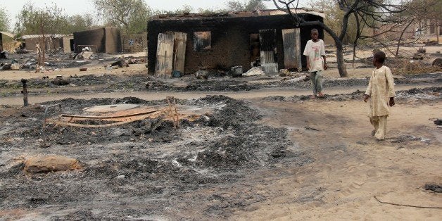 Children walk outside a charrred house in the remote northeast town of Baga on April 21, 2013 after two days of clashes between officers of the Joint Task Force and members of the Islamist sect Boko Haram on April 19 in the town near Lake Chad, 200 kms north of Maiduguri, in Borno State. Nigerian rescue workers set up temporary camps in Baga on April 25 and distributed aid to the masses displaced by brutal fighting that left 187 people dead. The bloodshed in Baga likely marked the deadliest-ever episode in the insurgency of Boko Haram, a radical group which has said it wants to create an Islamic state in northern Nigeria. AFP PHOTO / STR (Photo credit should read -/AFP/Getty Images)