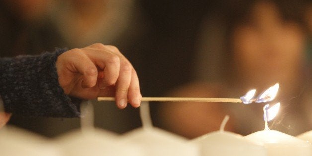 A girl lights a candle on January 11, 2015 at a ceremony at the Grand Synagogue in Paris for all the victims of the attacks in Paris this week, which claimed 17 lives. At least 3.7 million people marched against extremism across France, according to the Interior Ministry, in the biggest mobilisation ever recorded in the country after the Islamist attacks that killed 17 and shocked France. AFP PHOTO / POOL / MATTHIEU ALEXANDRE (Photo credit should read MATTHIEU ALEXANDRE/AFP/Getty Images)