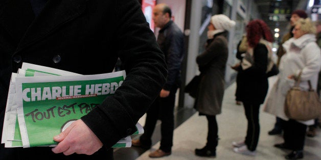 A man leaves after buying Charlie Hebdo newspapers as people queue at a newsstand in Paris, Wednesday, Jan. 14, 2015. In an emotional act of defiance, Charlie Hebdo resurrected its irreverent and often provocative newspaper, featuring a caricature of the Prophet Muhammad on the cover that drew immediate criticism and threats of more violence. (AP Photo/Christophe Ena)