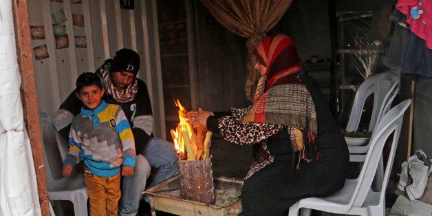 Members of a Palestinian family warm themselves inside their temporary housing after they lost their home during the war between Israel and Hamas in the summer, as severe weather passes through Khuzaa, east of Khan Younis in the southern Gaza Strip, Friday, Jan. 9, 2015. Heavy barrages of rain continued falling on the Gaza Strip on Friday after two days of cold, but mostly dry, winds. Ashraf al-Kidra, a spokesman for the Health Ministry, said a 2-month-old girl died of cold in Khan Younis in the southern Gaza Strip. (AP Photo/Adel Hana)