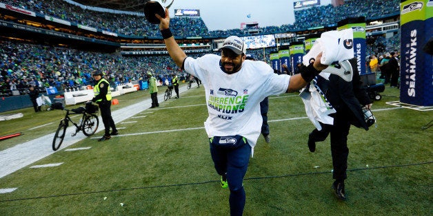 SEATTLE, WA - JANUARY 18: Russell Wilson #3 of the Seattle Seahawks holds up the George S. Halas trophy after the Seahawks 28-22 overtime victory against the Green Bay Packers in the 2015 NFC Championship game at CenturyLink Field on January 18, 2015 in Seattle, Washington. (Photo by Kevin C. Cox/Getty Images)