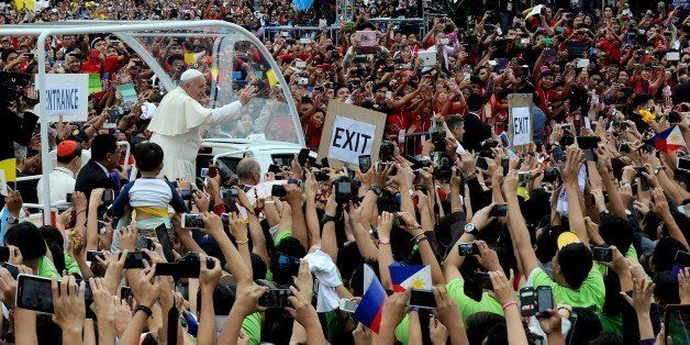 Pope Francis (L) waves as he arrives at the University of Santo Tomas during his visit to Manila on January 18, 2015. Pope Francis celebrated mass with millions of singing and cheering Catholics in the Philippine capital on January 18, in one of the world's biggest outpourings of papal devotion. AFP PHOTO / Jay DIRECTO (Photo credit should read JAY DIRECTO/AFP/Getty Images)