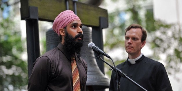 Simran Jeet Singh (L) of the Sikh Coalition speaks as the Reverend Matthew Heyd (R) of Trinity Wall Street listens before they ring the 'Bell of Hope' for the victims of the Sikh temple attack in Wisconsin in the courtyard of St. Paul's Chapel in New York on August 10, 2012. The bell was a gift from London to New York and is sounded for victims of terrible attacks and terrorism. AFP PHOTO/Stan HONDA (Photo credit should read STAN HONDA/AFP/GettyImages)