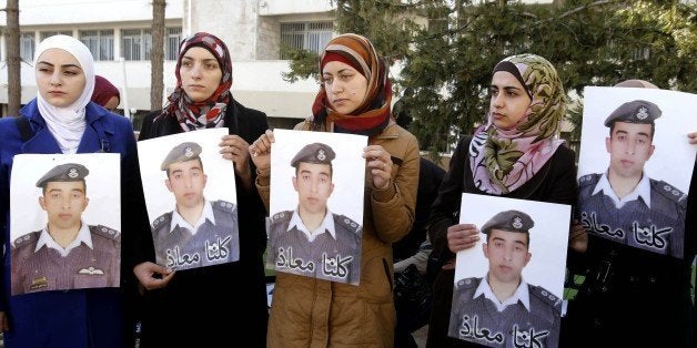 Anwar al-Tarawneh, center, the wife of Jordanian pilot, Lt. Muath al-Kaseasbeh, who is held by Islamic State group militants, holds a poster of him with Arabic that reads, "we are all Muath," during a protest in Amman, Jordan, Tuesday, Feb. 3, 2015. An online video released Tuesday, Feb. 3, 2015 purportedly shows a Jordanian pilot captured by the Islamic State extremist group being burned to death. The Associated Press was not immediately able to confirm the authenticity of the video, which was released on militant websites and bore the logo of the extremist group's al-Furqan media service. (AP Photo/Raad Adayleh)