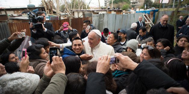 Pope Francis is welcomed by residents of a refugee camp in Ponte Mammolo, in the outskirts of Rome, as he made an unscheduled stop on his way to the San Michele Arcangelo Parish church to celebrate a mass in Rome, Sunday, Feb. 8, 2015. Francis prayed briefly before giving his blessing to the camp residents. (AP Photo/L'Osservatore Romano, pool)