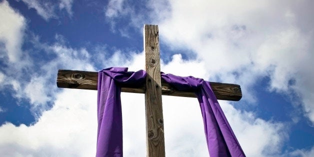 Back lit cross framed by bright sky and billowing clouds. Photo shot during the season of lent when the cross is to be veiled.