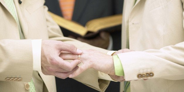 Man placing ring on another man's finger