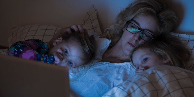 Family in bed watching television