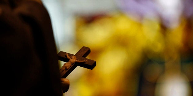 In this Dec. 1, 2012 photo, a statue with a crucifix and a stained glass window is seen inside a Catholic Church in New Orleans. Catholic groups are decrying a recent Louisiana Supreme Court decision that reaches into the most sanctified of Catholic places, the confessional booth. The high court has revived a sex abuse lawsuit in which parents are suing a priest and a local diocese for not reporting the alleged abuse when the teenager told the priest about it, and the ruling could have a priest asked to testify about what was said in a private confession. The Catholic League for Religious and Civil Rights says the ruling leaves the priest choosing between prison and excommunication, in a case that has grabbed attention in heavily Catholic south Louisiana. (AP Photo/Gerald Herbert)