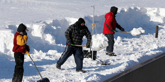 Workers clear snow from a roof in Boston, Monday, Feb. 16, 2015. New England remained bitterly cold Monday after the region's fourth winter storm in a month blew through. (AP Photo/Michael Dwyer)