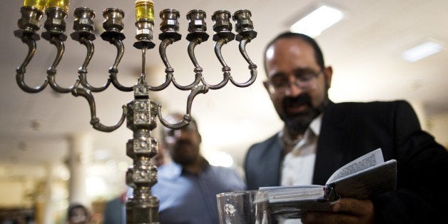 Iranian Jewish Rabbi Younes Hamami Lalehzar reads prayers after lighting candles to mark Hanukkah, the festival of lights, at
