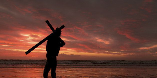 Man with a cross at a red sunset.