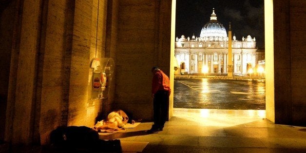 A volunteer of the Italian association 'City Angels' speaks with a homeless at the Vatican on November 18, 2014. City Angels