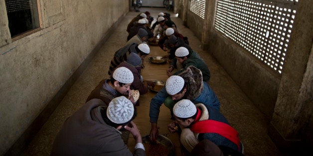 In this Sunday, Feb. 1, 2015 photo, Pakistani students of a madrassa, or Islamic school, eat their lunch at their seminary in