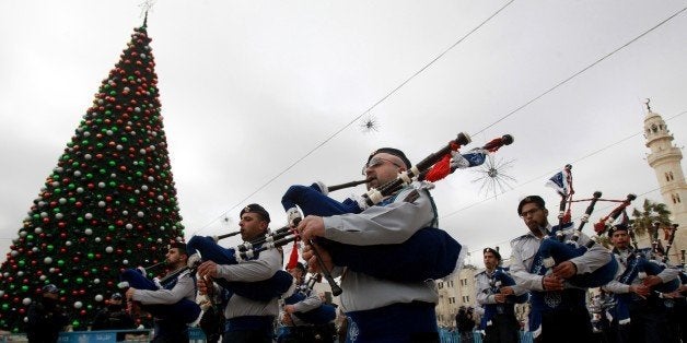 Palestinians play the bagpipes as they take part in celebrations for the Orthodox Christmas outside the Church of the Nativity in the biblical West Bank town of Bethlehem, believed to the be the birthplace of Jesus Christ, on January 6, 2015. AFP PHOTO / MUSA AL-SHAER (Photo credit should read MUSA AL-SHAER/AFP/Getty Images)