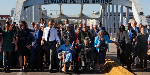 President Barack Obama, fourth from left, walks holding hands with Amelia Boynton Robinson, who was beaten during "Bloody Sunday," as they and the first family and others including Rep. John Lewis, D-Ga, left of Obama, walk across the Edmund Pettus Bridge in Selma, Ala,. for the 50th anniversary of the landmark event of the civil rights movement, Saturday, March 7, 2015. At far left is Sasha Obama and at far right is former first lady Laura Bush. Adelaide Sanford also sits in a wheelchair. (AP Photo/Jacquelyn Martin)