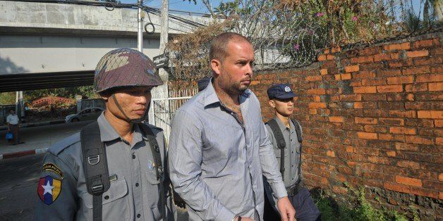 Phil Blackwood (C), a bar manager from New Zealand, is escorted by police as he arrives at a court for a hearing in Yangon on February 4, 2015. Blackwood is accused of insulting religion by using an image of Buddha to promote a cheap drinks night. The offending poster, which featured a psychedelic mock-up of the Buddha wearing DJ headphones, has prompted outcry in predominantly Buddhist Myanmar, which is grappling with surging religious nationalism. AFP PHOTO / SOE THAN WIN (Photo credit should read Soe Than WIN/AFP/Getty Images)