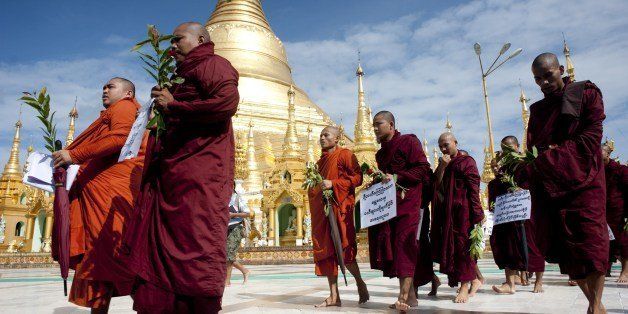 Monks carry posters of 'take action immediately against Jihad fundamentalists' while holding a prayer campaign at the fame Shwe Dagon Pagoda in Yangon on July 4, 2014. Myanmar's second-largest city was put under curfew after two people were killed in the latest outbreak of Buddhist-Muslim violence to convulse the former junta-ruled nation. AFP PHOTO / YE AUNG THU (Photo credit should read Ye Aung Thu/AFP/Getty Images)