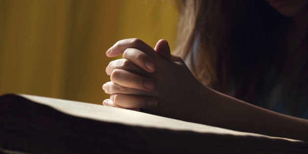 Girl praying with hands on 150 year old Bible