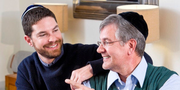 Senior Jewish man and adult son celebrating Hanukkah