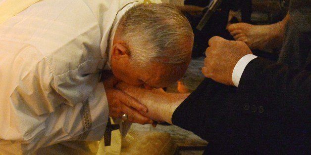 Pope Francis (L) kisses the foot of a person as he performs the traditional Washing of the feet during a visit at a center for disabled people as part of Holy Thursday (Maundy Thursday) as part of the Holy Week on April 17, 2014 in Rome. AFP PHOTO / ALBERTO PIZZOLI (Photo credit should read ALBERTO PIZZOLI/AFP/Getty Images)