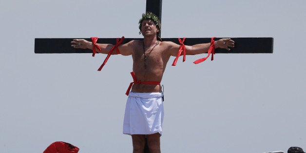 Danish national Lasse Spang Olsen, a 48-year-old filmmaker, stays nailed to a cross to re-enact the crucifixion of Jesus Christ in San Pedro Cutud village, Pampanga province, northern Philippines on Friday, April 18, 2014. Church leaders and health officials have spoken against the practice which mixes Roman Catholic devotion with folk belief, but the annual rites continue to draw participants and huge crowds. (AP Photo/Aaron Favila)