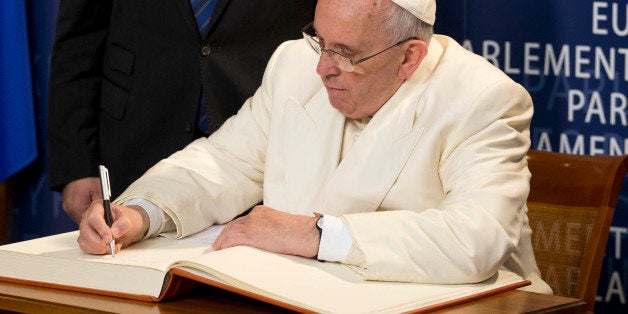 Pope Francis signs the guest book as President of the European Parliament Martin Schulz stands behind him, at the European Parliament in Strasbourg, France, Tuesday, Nov. 25, 2014. Pope Francis has demanded Europe craft a unified and fair immigration policy, saying the thousands of refugees coming ashore need acceptance and assistance, not self-interested policies that risk lives and fuel social conflict. Francis made the comments Tuesday to the European Parliament during a brief visit meant to highlight his vision for Europe a quarter-century after St. John Paul II travelled to Strasbourg to address a continent still divided by the Iron Curtain. (AP Photo/Andrew Medichini)