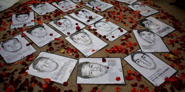 Drawings of some of 43 missing students are surrounded by flower petals, formimg the shape of a heart, during a protest marki
