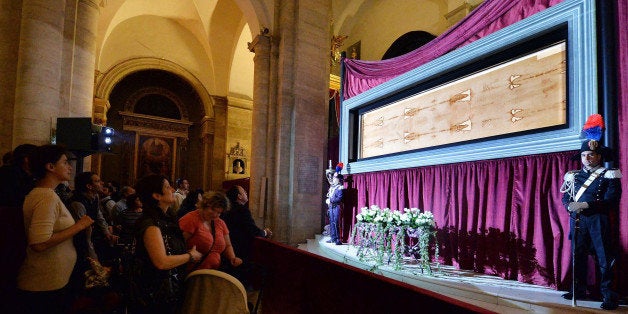 Pilgrims stop by the Holy Shroud, the 14 foot-long linen revered by some as the burial cloth of Jesus, displayed at the Cathedral of Turin, in Turin, Italy, 20 April 2015. The long linen with the faded image of a bearded man, that is the object of centuries-old fascination and wonderment, will be on display for the public from April 19 to June 24, 2015. Pope Francis said he is planning to visit the Holy Shroud during a a pilgrimage to Turin next June 21, 2015. Alessandro Di Marco/ANSA via AP) ITALY OUT