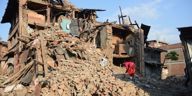 A woman walks amidst the rubble of collapsed houses in Bhaktapur, on the outskirts of Kathmandu, on April 27, 2015, two days