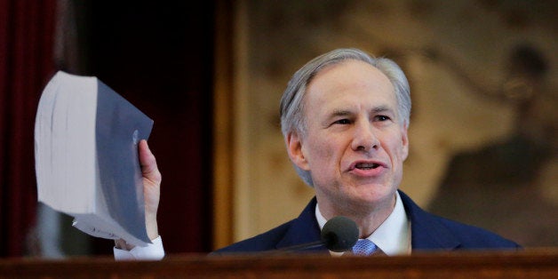 Texas Gov. Greg Abbott holds a book about Texas school laws as he delivers his State of the State address to a joint session