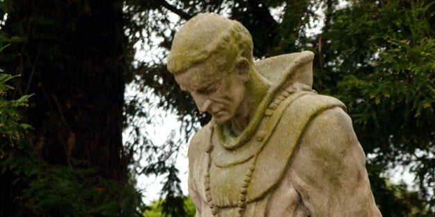 Andrew Galvan, the first American Indian curator of Mission Dolores, looks over a statue of Father Junipero Serra, in the cemetary of the historic church in San Francisco, Feb. 17, 2004. (AP Photo/Eric Risberg)