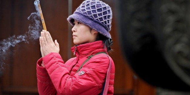 A woman burns incense sticks at a temple in Shanghai on February 16, 2010 during the Spring Festival. The Chinese are currently in the midst of Spring Festival, a week-long holiday marking the beginning of the new year which sees families around the country of 1.3 billion reunite and attend traditional temple fairs. AFP PHOTO / PHILIPPE LOPEZ (Photo credit should read PHILIPPE LOPEZ/AFP/Getty Images)