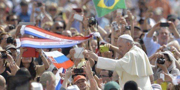 Pilgrims wave Slovakian and Brazilian flags as Pope Francis greets the crowd from the popemobile before his weekly general audience at St Peter's square on May 6, 2015 at the Vatican. AFP PHOTO / ANDREAS SOLARO (Photo credit should read ANDREAS SOLARO/AFP/Getty Images)