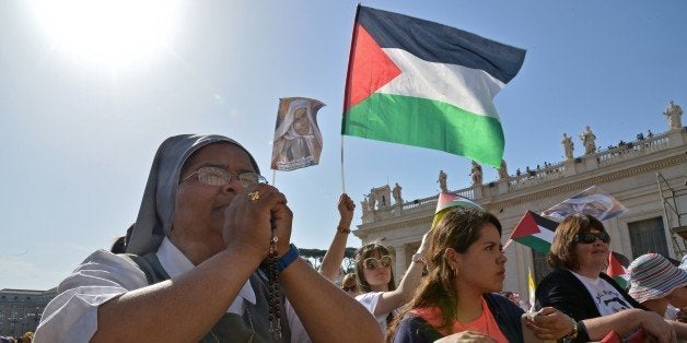 Pilgrims wave Palestinian flags before a holy mass in St Peter's square for the canonization of four blessed nuns, whose two lived in Ottoman Palestine, on May 17, 2015 in Vatican. Pope Francis will declare four nuns as Saints today, two nuns from Palestine St Marie Alphonsine Ghattas from Jerusalem and St Mariam Bawardy from Ibilin village in the Galilee, both of whom lived in the 19th century, St Emilie de Villeneuve from France and St Maria Cristina of the Immaculate Conception from Italy. AFP PHOTO / ALBERTO PIZZOLI (Photo credit should read ALBERTO PIZZOLI/AFP/Getty Images)