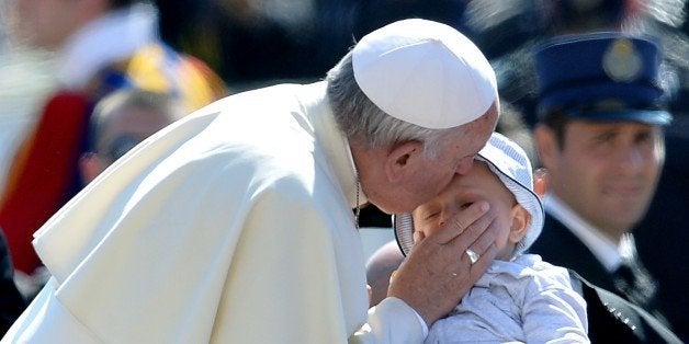 Pope Francis kiss a baby as he arrives for his weekly general audience in St Peter's square at the Vatican on May 27, 2015.